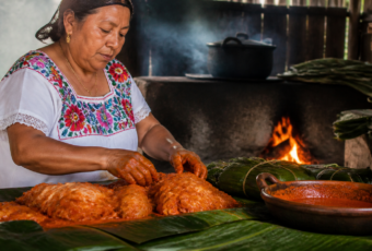 Cocinera yucateca abre un horno de tierra con una olla de cochinita pibil envuelta en hojas.